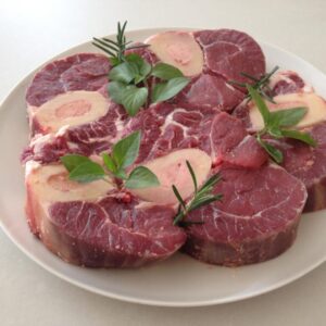 "A beautifully braised beef shin served on a rustic plate, garnished with fresh herbs, alongside a hearty vegetable stew and a slice of crusty bread."