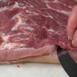 A well-trimmed piece of frozen beef, displaying minimal fat and sinew, laid out on a cutting board. The beef is ready for cooking, emphasizing its quality and the precision of the trimming process. Fresh herbs and a sharp knife are in the background, suggesting preparation for a delicious meal.