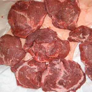 portion of frozen buffalo cheek meat, showcasing its rich red color and marbling, ready for cooking.